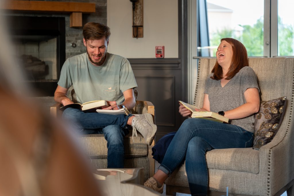 People laughing while reading books together.